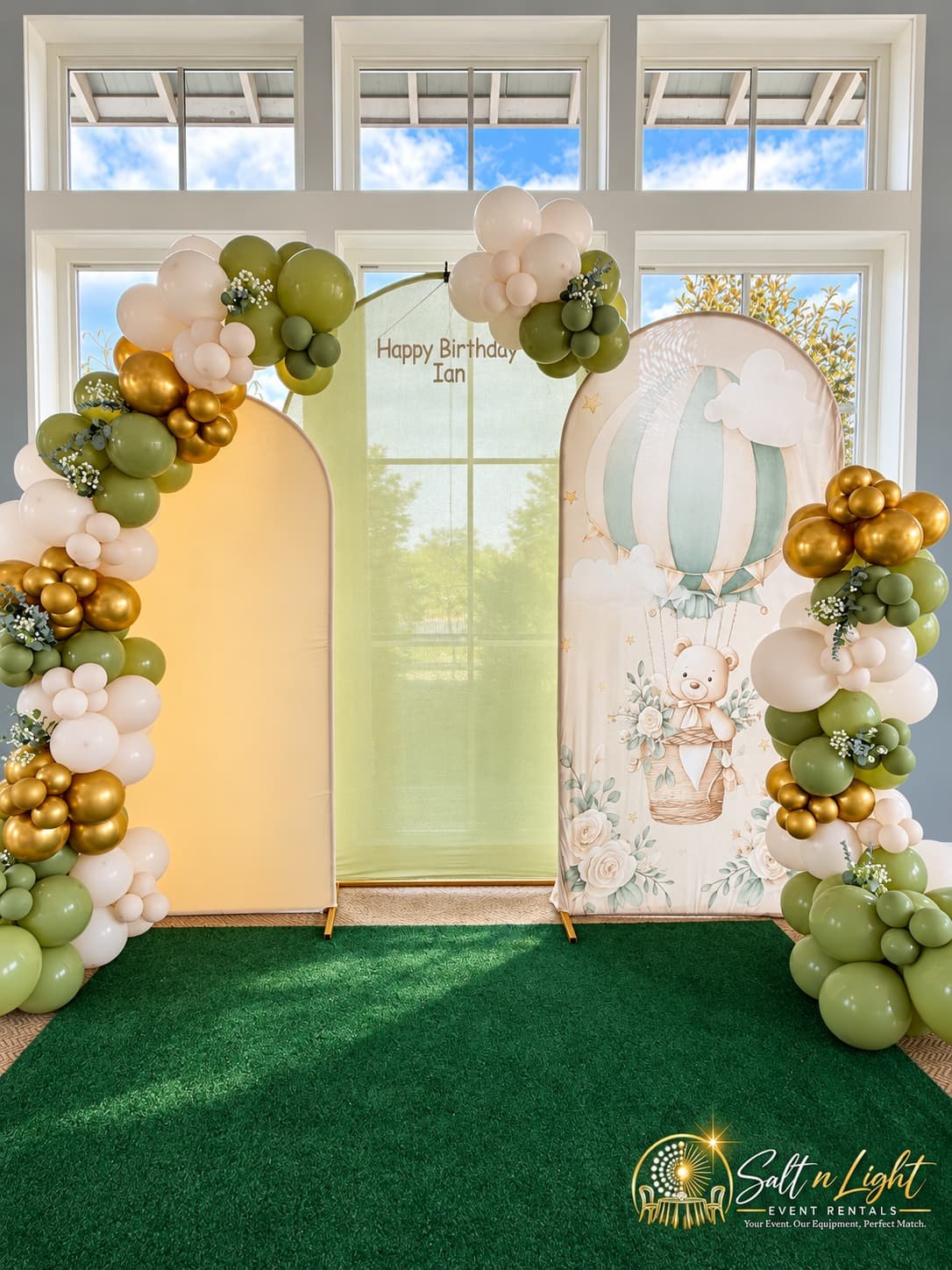 First birthday focal backdrop with sage, cream and gold balloons and illustrated decorative panels