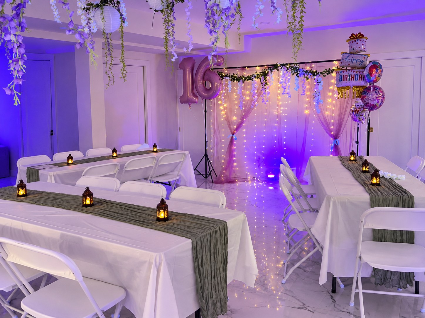 White folding chairs and linen-covered tables facing a draped birthday backdrop with pink 16 balloons