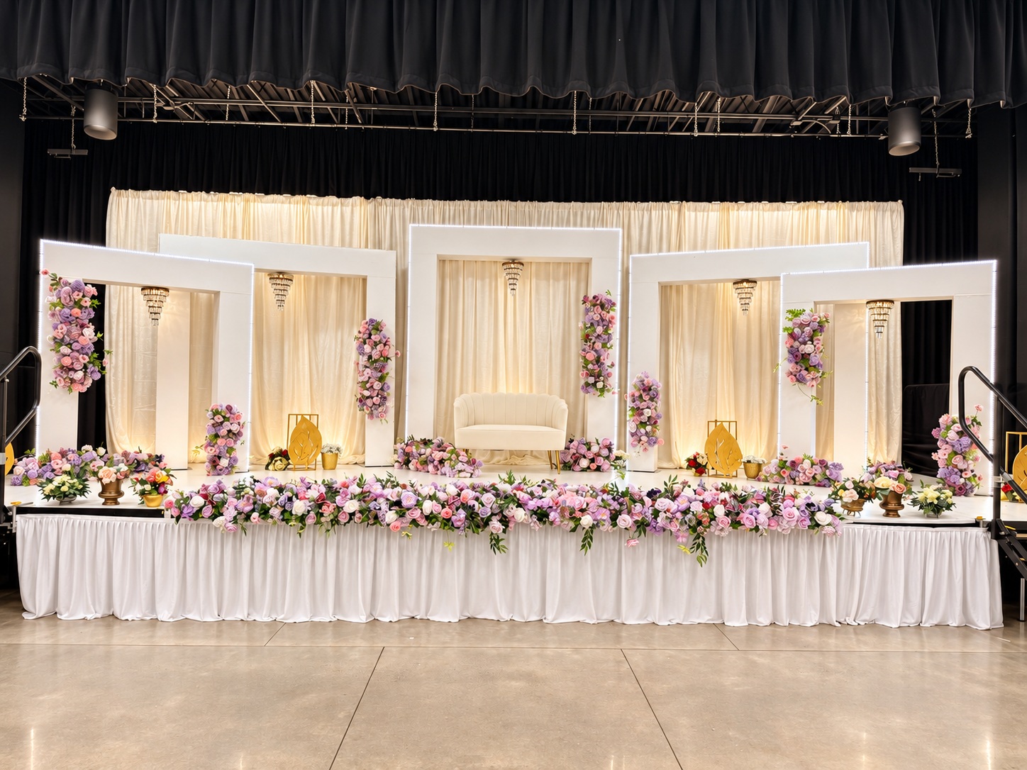 Pink and lavender floral wedding stage viewed from the reception floor.