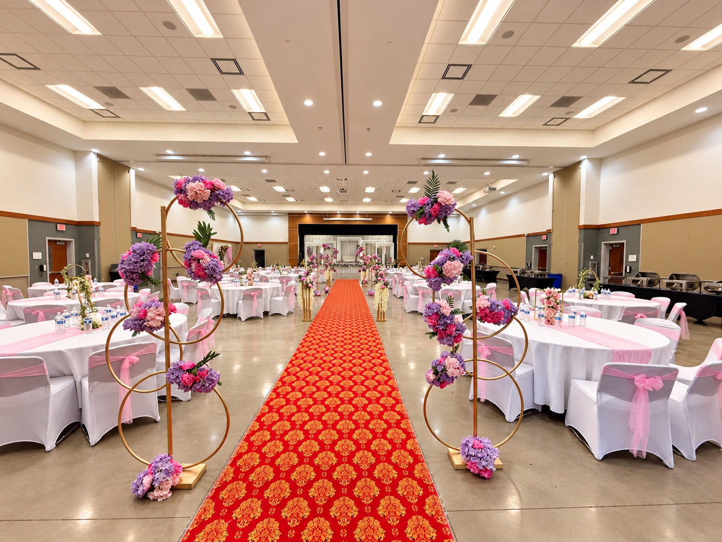 Wedding reception aisle leading through round guest tables toward a floral stage.
