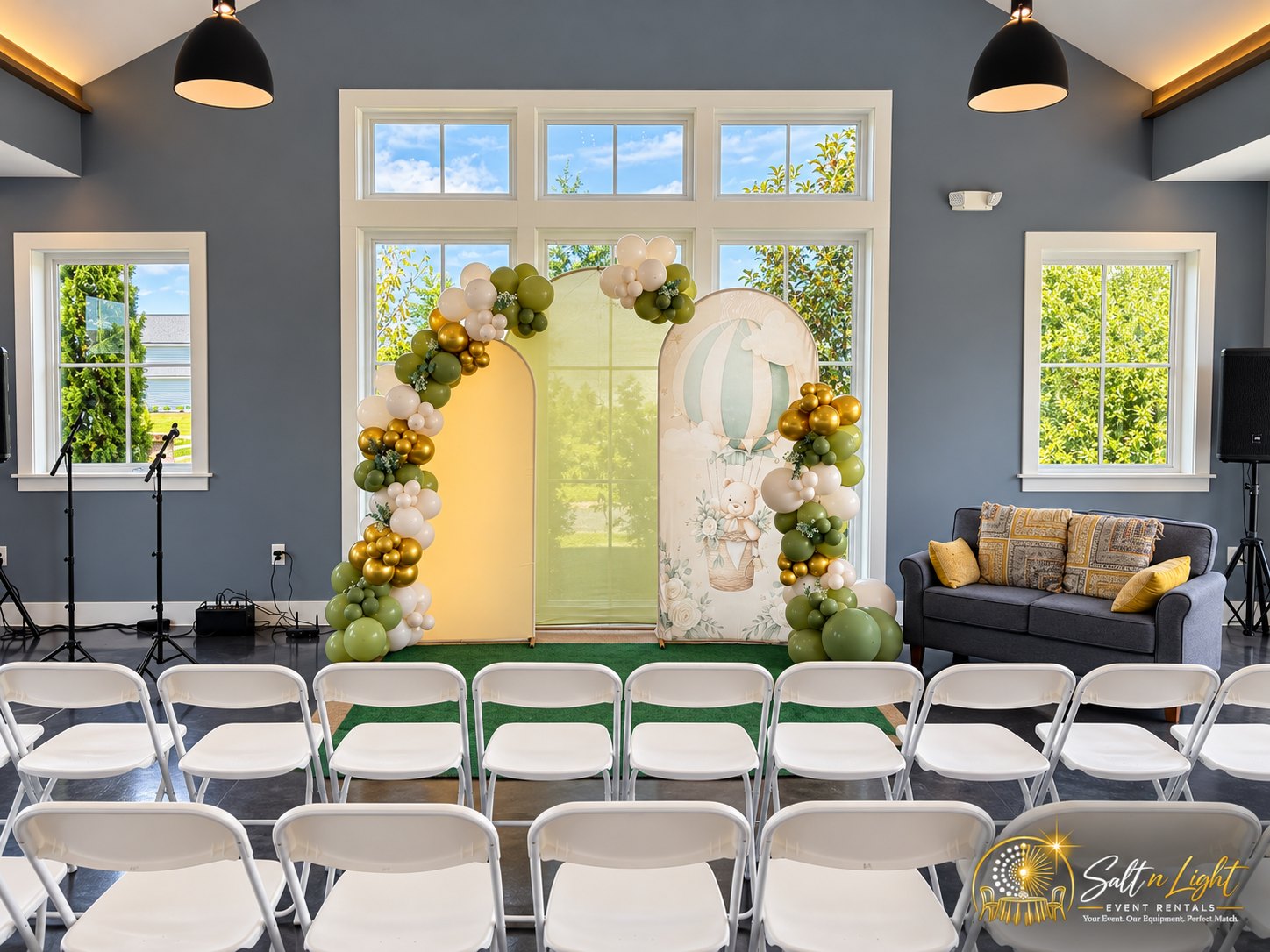Rows of white folding chairs facing the birthday backdrop and audio setup inside the event room